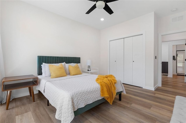 bedroom featuring baseboards, wood finished floors, visible vents, and a closet