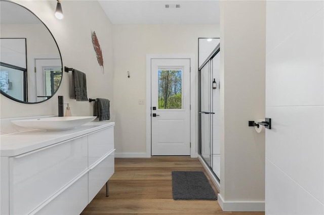 full bathroom featuring a shower stall, wood finished floors, visible vents, and baseboards