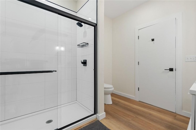 bathroom with baseboards, wood finished floors, a shower stall, and toilet