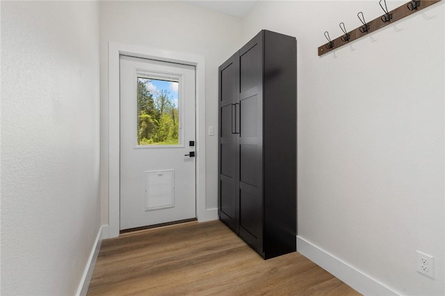 doorway to outside featuring light wood-style flooring and baseboards