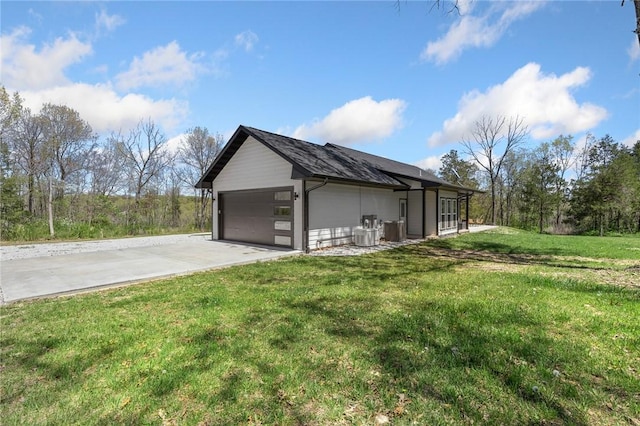 view of side of property featuring a garage, central air condition unit, a lawn, and concrete driveway