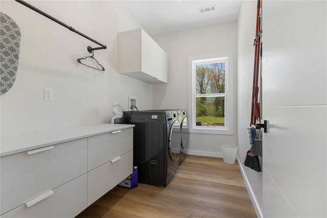laundry room with light wood-style floors, washer and dryer, cabinet space, baseboards, and visible vents