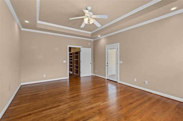 empty room with baseboards, a ceiling fan, wood finished floors, crown molding, and a raised ceiling