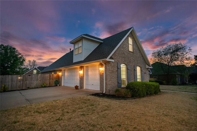 view of front of house with concrete driveway, a front lawn, fence, and brick siding