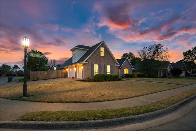 view of front of home with driveway, an attached garage, fence, a front yard, and brick siding