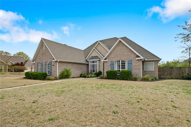 ranch-style home featuring brick siding, fence, and a front yard