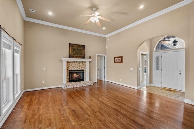 unfurnished living room featuring baseboards, wood finished floors, ornamental molding, and ceiling fan