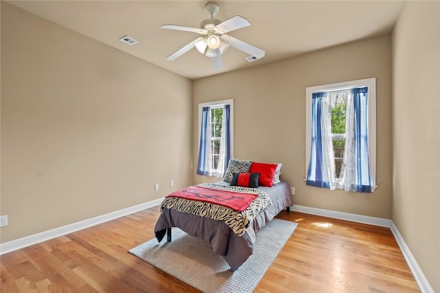 bedroom featuring baseboards, light wood-style flooring, visible vents, and multiple windows