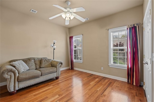 living area with baseboards, visible vents, light wood finished floors, and a wealth of natural light