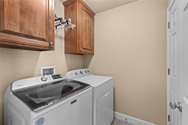 washroom with cabinet space, baseboards, and separate washer and dryer