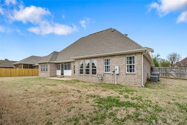 back of house featuring central AC unit, a fenced backyard, a patio, a lawn, and brick siding