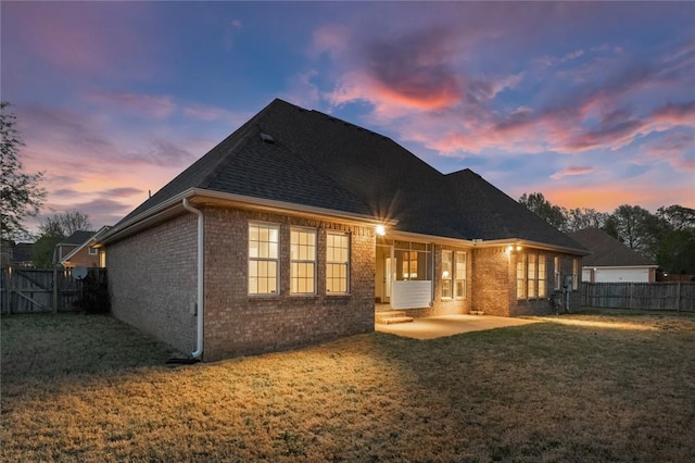 rear view of house with a fenced backyard, brick siding, a patio, and a lawn