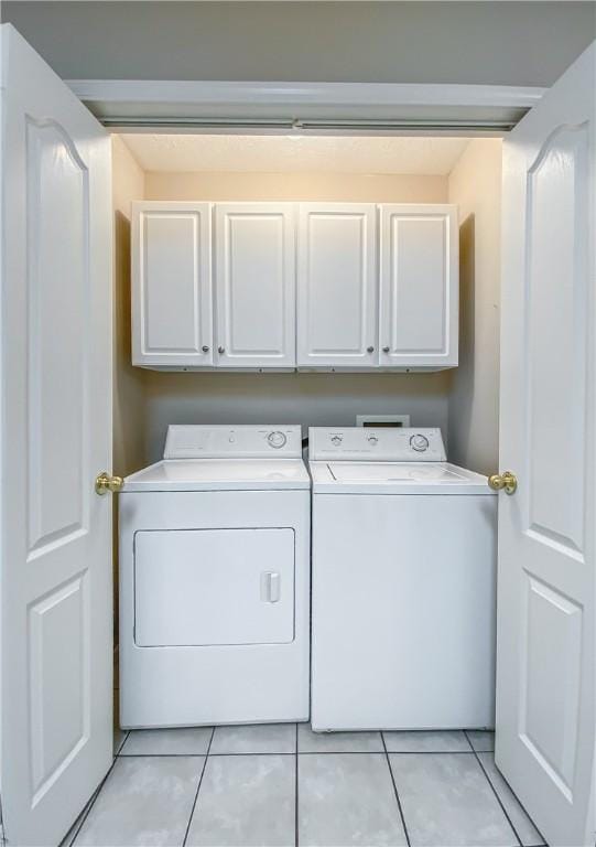 washroom with separate washer and dryer, cabinet space, and light tile patterned flooring