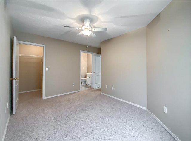 unfurnished bedroom featuring a walk in closet, baseboards, and light carpet