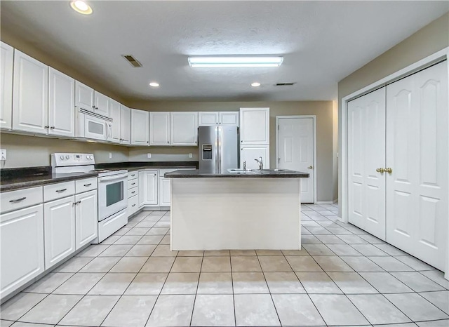 kitchen featuring dark countertops, white appliances, white cabinetry, and light tile patterned floors
