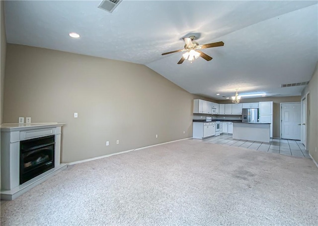 unfurnished living room featuring visible vents, baseboards, a fireplace, light colored carpet, and ceiling fan with notable chandelier