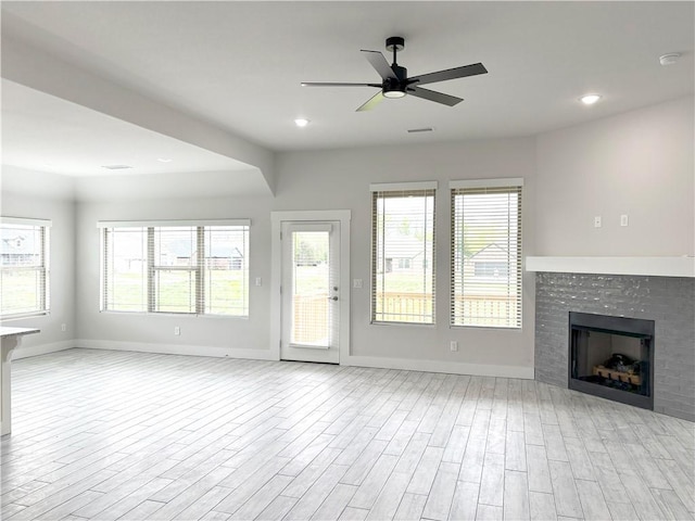 unfurnished living room featuring baseboards, a ceiling fan, wood finished floors, and a fireplace