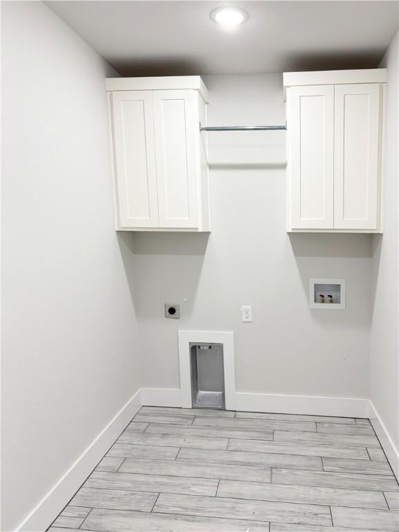 washroom with electric dryer hookup, cabinet space, light wood finished floors, baseboards, and washer hookup