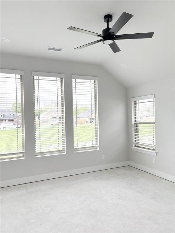 empty room featuring unfinished concrete floors, a healthy amount of sunlight, a ceiling fan, and baseboards