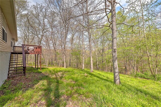 view of yard featuring a wooded view, stairs, and a deck