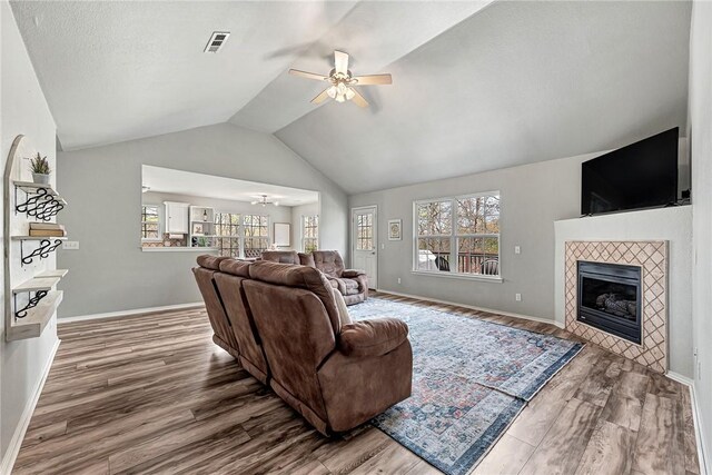 living room featuring vaulted ceiling, wood finished floors, visible vents, and a ceiling fan