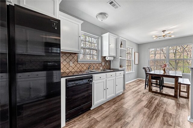 kitchen featuring an inviting chandelier, dark countertops, wood finished floors, visible vents, and black appliances