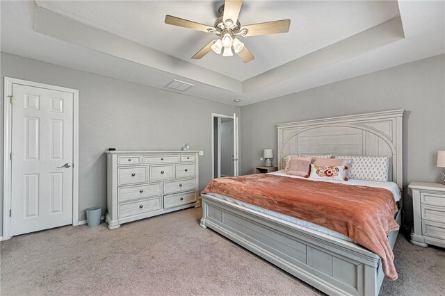 bedroom with a ceiling fan, visible vents, carpet floors, and a raised ceiling