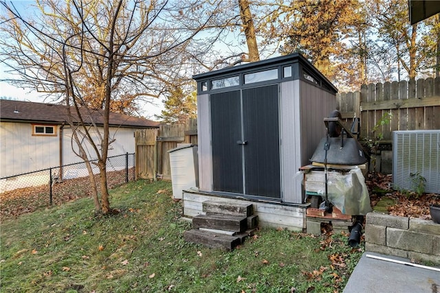view of shed featuring entry steps, a fenced backyard, and central AC unit