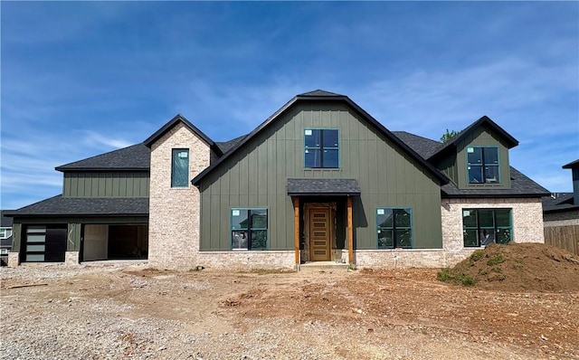 view of front of house featuring a shingled roof, board and batten siding, and stone siding