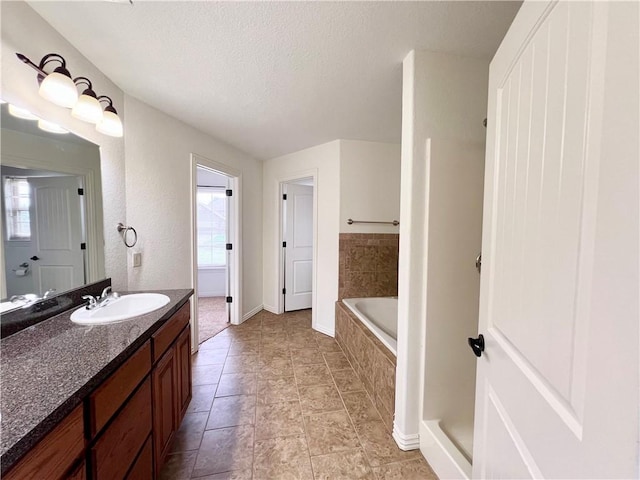 1650 Affirmed Ln, Prairie Grove, AR 72753 - bathroom with vanity, a relaxing tiled tub, and a textured ceiling