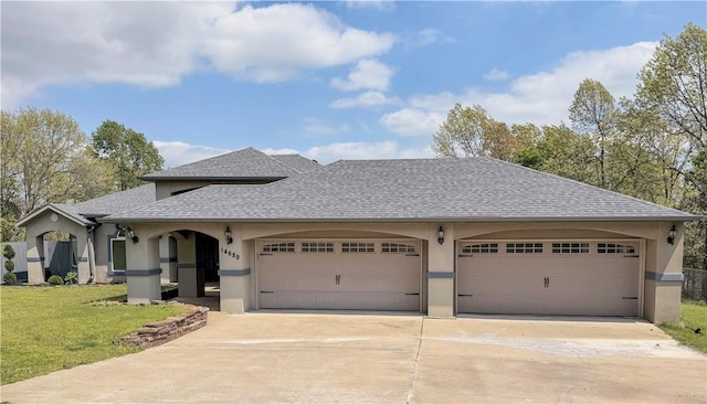 view of front of house with roof with shingles, an attached garage, stucco siding, a front yard, and driveway