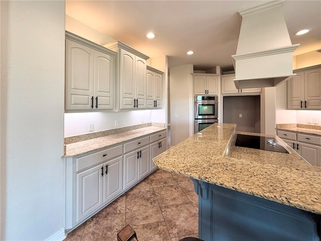 kitchen with light stone countertops, double oven, black electric cooktop, recessed lighting, and custom exhaust hood