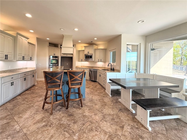 kitchen with a kitchen breakfast bar, a center island, recessed lighting, a sink, and appliances with stainless steel finishes