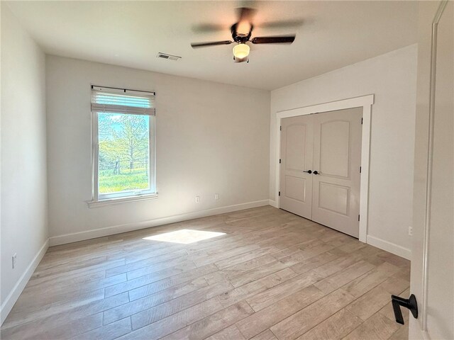 unfurnished room featuring visible vents, a ceiling fan, light wood finished floors, and baseboards