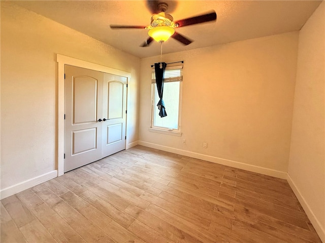 unfurnished room with a ceiling fan, baseboards, and light wood-style flooring