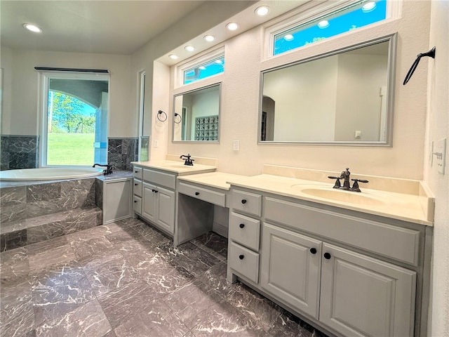 bathroom featuring a sink, double vanity, marble finish floor, recessed lighting, and a garden tub