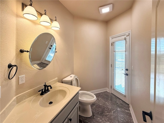 half bath featuring baseboards, vanity, toilet, marble finish floor, and a textured wall