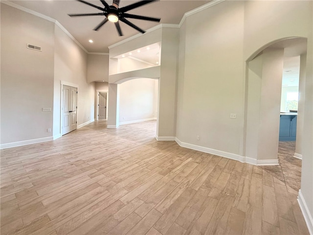 spare room with a ceiling fan, visible vents, arched walkways, light wood finished floors, and ornamental molding