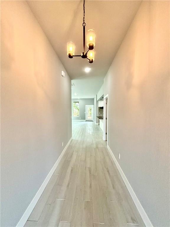 708 W Taylor St, Siloam Springs, AR 72761 - hallway featuring a chandelier, light wood-type flooring, and baseboards