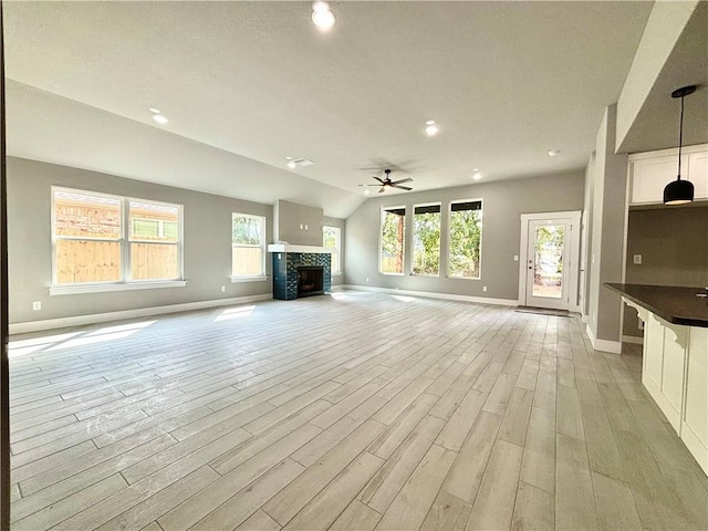 708 W Taylor St, Siloam Springs, AR 72761 - unfurnished living room with light wood finished floors, a ceiling fan, baseboards, and a fireplace