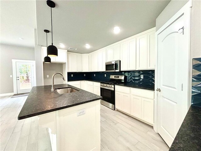 708 W Taylor St, Siloam Springs, AR 72761 - kitchen with light wood finished floors, stainless steel appliances, white cabinets, a sink, and tasteful backsplash