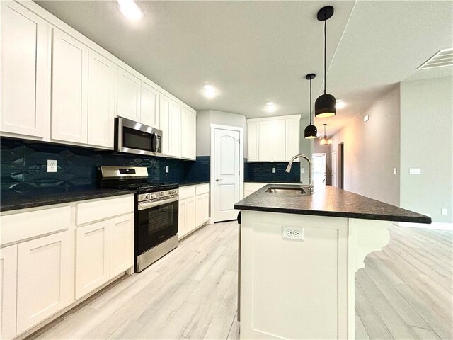 708 W Taylor St, Siloam Springs, AR 72761 - kitchen with dark countertops, a sink, decorative backsplash, light wood-style floors, and appliances with stainless steel finishes