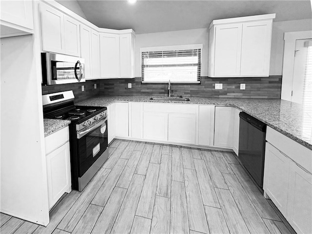 kitchen featuring white cabinets, a sink, backsplash, light stone counters, and appliances with stainless steel finishes