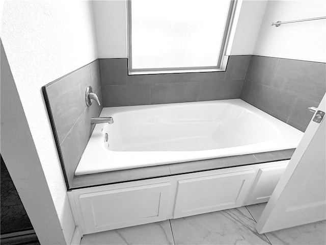 bathroom featuring a bath and marble finish floor