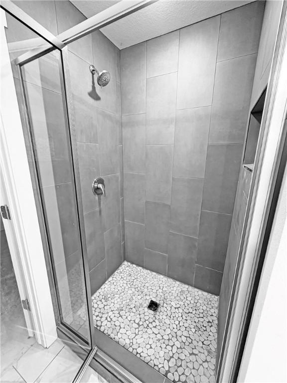 full bath with marble finish floor and a shower stall