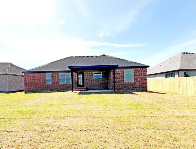 back of house featuring brick siding, a yard, and fence