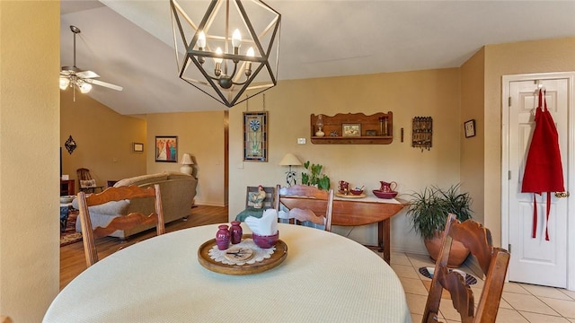 dining space featuring ceiling fan with notable chandelier, light tile patterned floors, and lofted ceiling