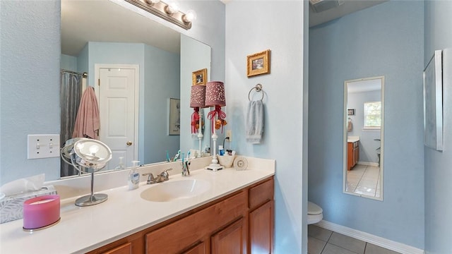 bathroom with baseboards, vanity, tile patterned flooring, and toilet