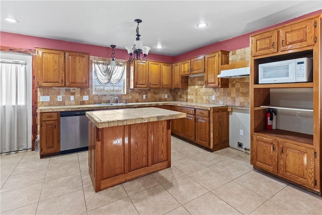 kitchen with stainless steel dishwasher, a sink, white microwave, brown cabinets, and under cabinet range hood