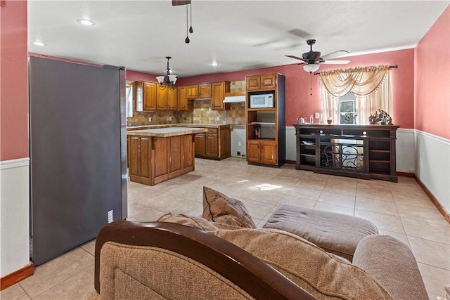 living area featuring a ceiling fan, baseboards, and light tile patterned floors